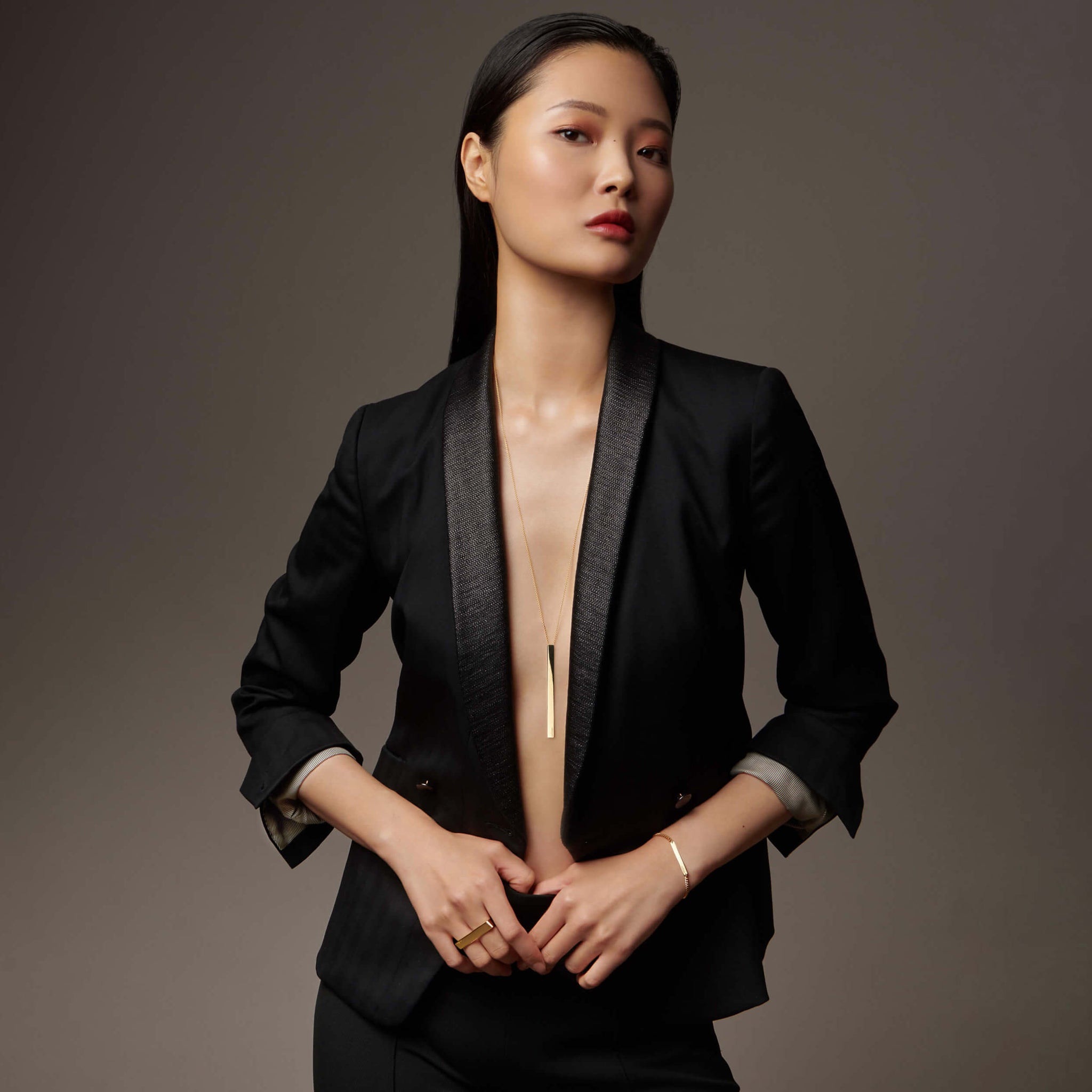 Woman standing with suit jacket on wearing atelium jewelry