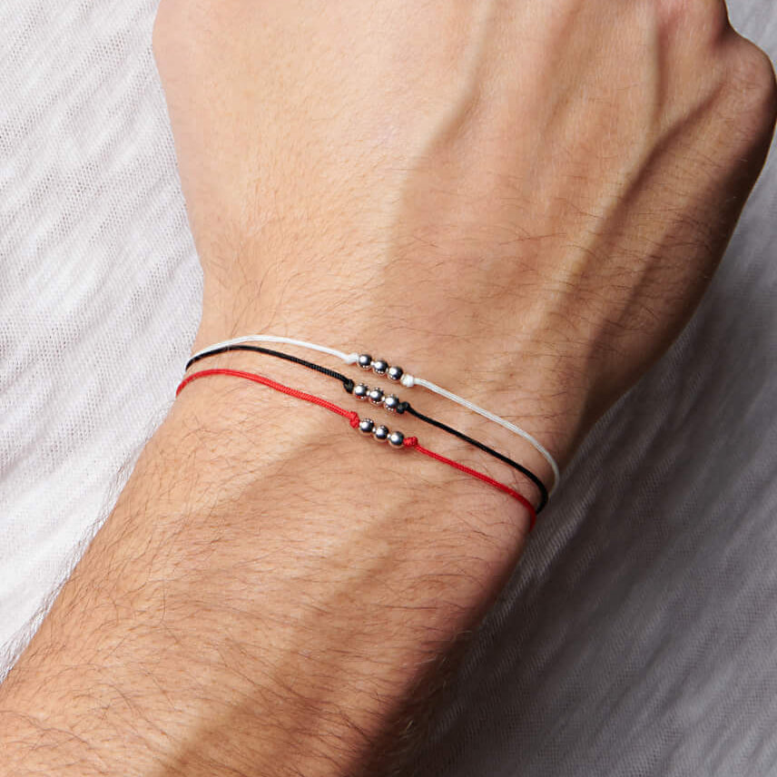 Up close image of wrist with 3 string bracelets