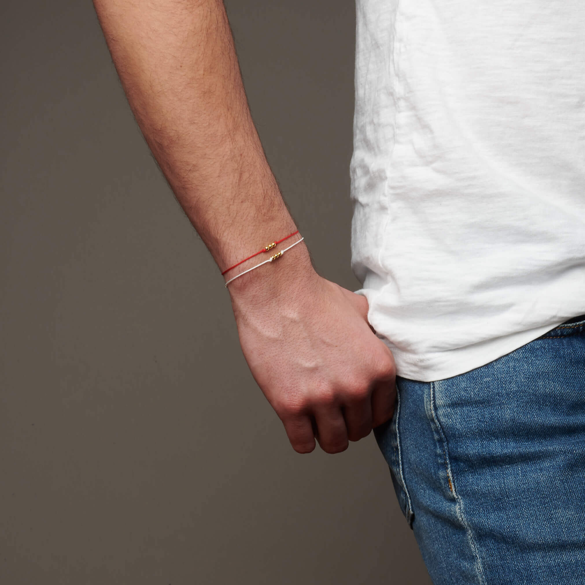 Hand on hip facing forward showing wrist wearing 2 string bracelets
