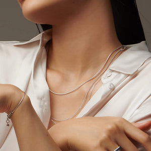 Up close shot of a woman's neck wearing a silver atelium necklace and bracelet