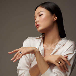 Woman's torso and crossed arms wearing atelium silver rings and necklaces