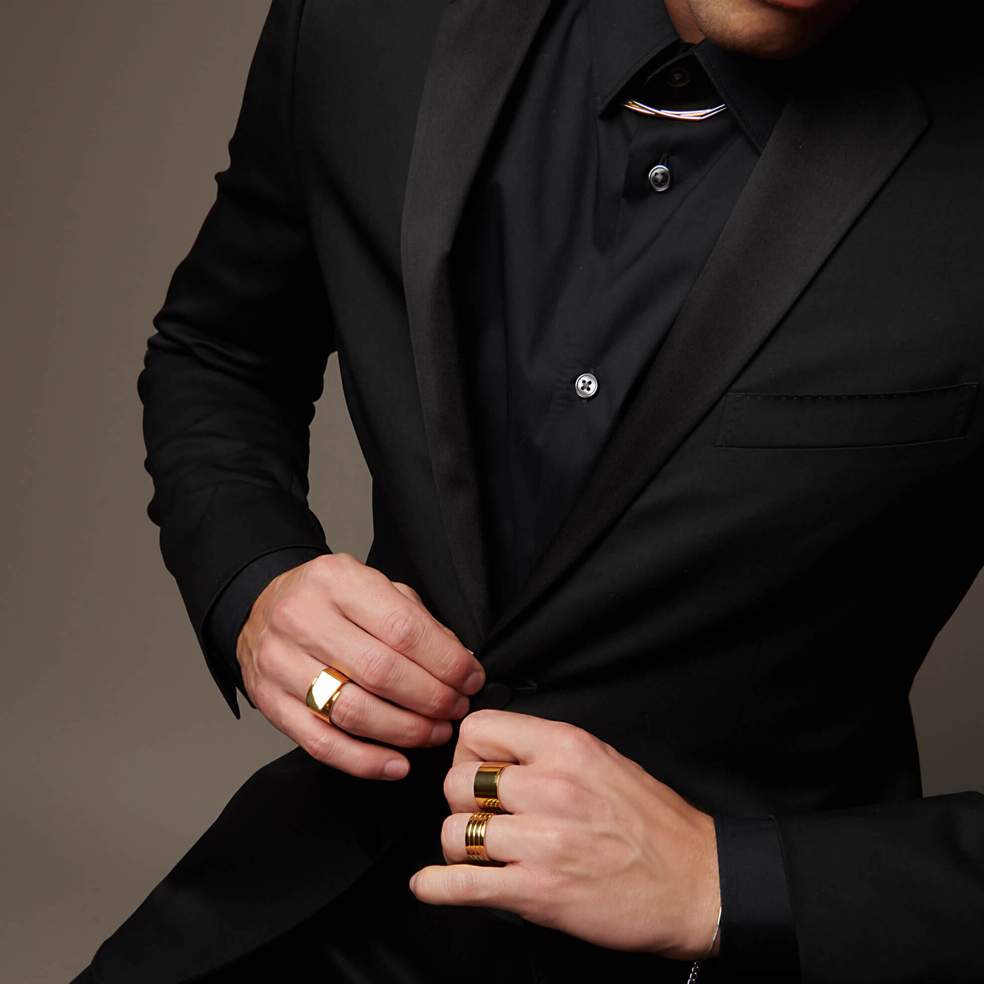Man buttoning suit jacket wearing atelium rings