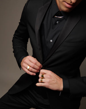 Man buttoning suit wearing atelium jewelry