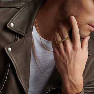 Up close picture of man's jaw, neck, and hand wearing atelium gold ring and necklace