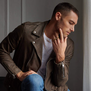 Man sitting with hand on face wearing atelium jewelry