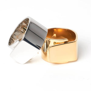 Wide gold ring with overlapping sides and silver ring with overlapping sides stacked offset